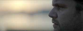 Movie still from “Suntan” (2016), directed by Argyris Papadimitropoulos – A man's face with a blurry background; Extreme Close Up shot, Low angle