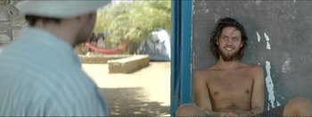 Movie still from “Suntan” (2016), directed by Argyris Papadimitropoulos – A young boy sitting on a ledge in a park; Medium shot, Over the shoulder angle