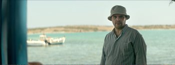 Movie still from “Suntan” (2016), directed by Argyris Papadimitropoulos – A man standing in front of a body of water; Medium shot, Over the shoulder angle