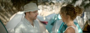 Movie still from “Suntan” (2016), directed by Argyris Papadimitropoulos – A man wearing a hat talking to a woman outside; Close Up shot, Over the shoulder angle