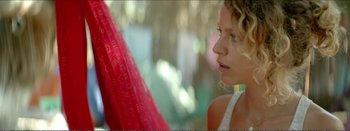 Movie still from “Suntan” (2016), directed by Argyris Papadimitropoulos – A young woman is standing in front of a red hammock; Close Up shot, Over the shoulder angle