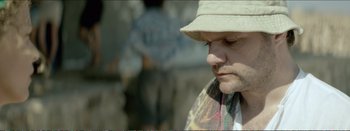 Movie still from “Suntan” (2016), directed by Argyris Papadimitropoulos – A person wearing a hat; Close Up shot, Over the shoulder angle