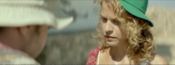 Movie still from “Suntan” (2016), directed by Argyris Papadimitropoulos – A young girl with blonde curly hair is looking down; Close Up shot, Over the shoulder angle