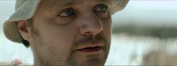 Movie still from “Suntan” (2016), directed by Argyris Papadimitropoulos – A man's face with green eyes; Extreme Close Up shot, Over the shoulder angle
