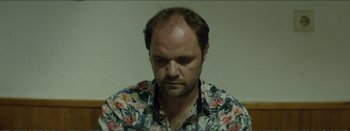Movie still from “Suntan” (2016), directed by Argyris Papadimitropoulos – A person wearing a floral shirt; Close Up shot, Low angle