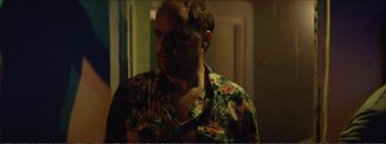 Movie still from “Suntan” (2016), directed by Argyris Papadimitropoulos – A man wearing a hawaiian shirt is looking at the camera; Medium shot, Over the shoulder angle