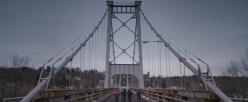 Movie still from “Super Dark Times” (2017), directed by Kevin Phillips – A group of bicyclists riding across a suspension bridge; Extreme Wide shot, Low angle