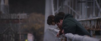 Movie still from “Super Dark Times” (2017), directed by Kevin Phillips – Two young people leaning over a railing looking at a cell phone; Medium shot, Over the shoulder angle