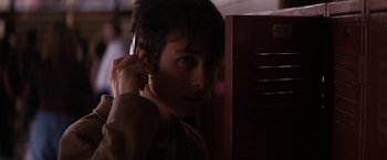 Movie still from “Super Dark Times” (2017), directed by Kevin Phillips – A young man with headphones in front of a red cabinet; Close Up shot, Over the shoulder angle