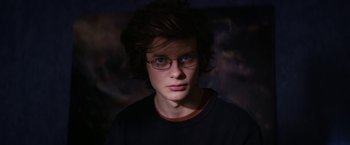 Movie still from “Super Dark Times” (2017), directed by Kevin Phillips – A young man wearing glasses and a black t - shirt; Close Up shot, Low angle