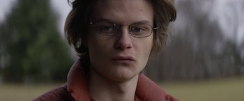 Movie still from “Super Dark Times” (2017), directed by Kevin Phillips – A person wearing glasses and a jacket; Close Up shot, Low angle