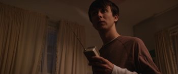 Movie still from “Super Dark Times” (2017), directed by Kevin Phillips – A young man holding a cell phone in his hand; Close Up shot, Low angle