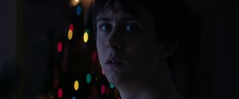 Movie still from “Super Dark Times” (2017), directed by Kevin Phillips – A young man stares into the distance in front of lights; Close Up shot, Low angle