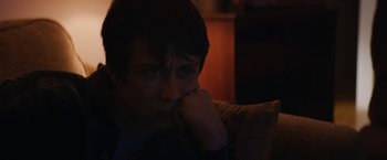 Movie still from “Super Dark Times” (2017), directed by Kevin Phillips – A man sitting on a couch with his hand under his chin; Close Up shot, Over the shoulder angle