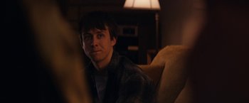 Movie still from “Super Dark Times” (2017), directed by Kevin Phillips – A man sitting on a couch in a living room; Close Up shot, Over the shoulder angle