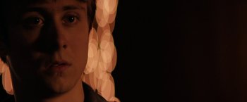 Movie still from “Super Dark Times” (2017), directed by Kevin Phillips – A man is looking at the camera in front of some lights; Extreme Close Up shot, Over the shoulder angle