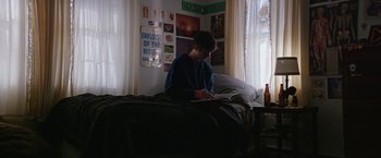 Movie still from “Super Dark Times” (2017), directed by Kevin Phillips – A person sitting on a bed writing in a notebook; Medium shot, High angle
