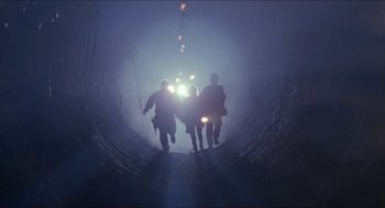 Movie still from “Super Mario Bros.” (1993), directed by Annabel Jankel – A group of people walking down a road in the fog; Extreme Wide shot, Low angle