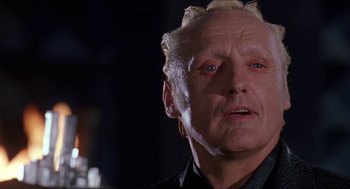 Movie still from “Super Mario Bros.” (1993), directed by Annabel Jankel – An older man with a white hair and a black shirt; Close Up shot, Low angle