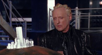 Movie still from “Super Mario Bros.” (1993), directed by Annabel Jankel – A man with blonde hair and a black shirt; Close Up shot, Over the shoulder angle