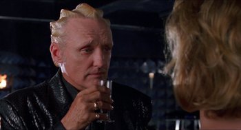 Movie still from “Super Mario Bros.” (1993), directed by Annabel Jankel – A man in a leather jacket holding a glass of wine; Close Up shot, Over the shoulder angle