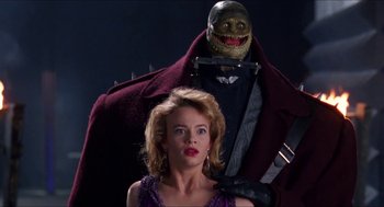 Movie still from “Super Mario Bros.” (1993), directed by Annabel Jankel – A woman standing in front of a man with a knife in his hand; Medium shot, Low angle