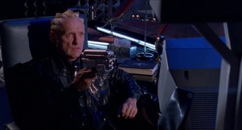 Movie still from “Super Mario Bros.” (1993), directed by Annabel Jankel – A man sitting in front of a computer holding a gun; Medium shot, Over the shoulder angle