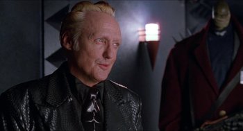 Movie still from “Super Mario Bros.” (1993), directed by Annabel Jankel – An older man in a leather jacket and a tie; Close Up shot, Over the shoulder angle
