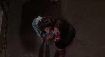 Movie still from “Super Mario Bros.” (1993), directed by Annabel Jankel – Two young girls standing next to each other in a dark room; Medium shot, Overhead angle