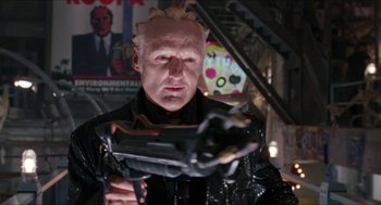 Movie still from “Super Mario Bros.” (1993), directed by Annabel Jankel – A man in a leather jacket holding a gun in his hand; Close Up shot, Low angle