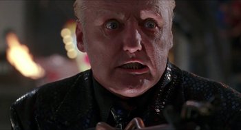 Movie still from “Super Mario Bros.” (1993), directed by Annabel Jankel – An older man in a suit and tie looking at the camera; Close Up shot, Low angle
