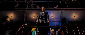 Movie still from “Surrogates” (2009), directed by Jonathan Mostow – A man in a suit and bow tie standing in front of a crowd of onlookers; Wide shot, Low angle