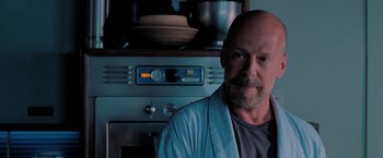 Movie still from “Surrogates” (2009), directed by Jonathan Mostow – A bald man with a beard and a towel around his neck is in front of an oven; Close Up shot, Over the shoulder angle
