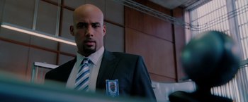 Movie still from “Surrogates” (2009), directed by Jonathan Mostow – A man in a suit and tie holding a badge; Close Up shot, Low angle