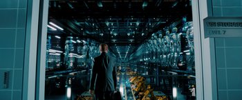 Movie still from “Surrogates” (2009), directed by Jonathan Mostow – A man in a suit is standing in an industrial setting; Wide shot, High angle