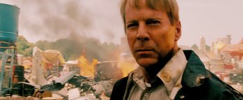 Movie still from “Surrogates” (2009), directed by Jonathan Mostow – A person in front of a burning building; Close Up shot, Low angle
