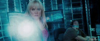 Movie still from “Surrogates” (2009), directed by Jonathan Mostow – A woman standing in a room with a light shining on her face; Medium shot, Over the shoulder angle