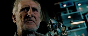 Movie still from “Surrogates” (2009), directed by Jonathan Mostow – An older man with a beard and glasses in front of a mirror; Close Up shot, Low angle