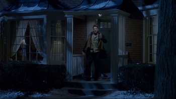 Movie still from “Surviving Christmas” (2004), directed by Mike Mitchell – A man standing on the porch of a house at night; Wide shot, Low angle