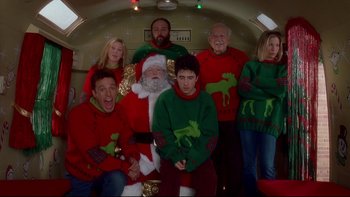 Movie still from “Surviving Christmas” (2004), directed by Mike Mitchell – A group of people wearing christmas sweaters posing for a picture; Medium shot, Overhead angle