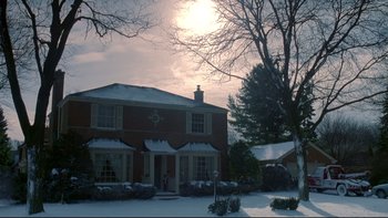 Movie still from “Surviving Christmas” (2004), directed by Mike Mitchell – A brick house with snow on the ground and trees in the background; Extreme Wide shot, Low angle