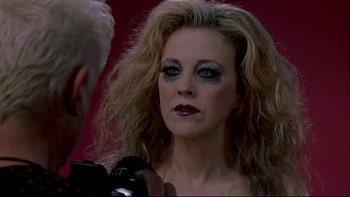 Movie still from “Surviving Christmas” (2004), directed by Mike Mitchell – A woman with makeup on her face is being photographed; Close Up shot, Over the shoulder angle