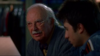 Movie still from “Surviving Christmas” (2004), directed by Mike Mitchell – An older man wearing glasses and a sweater; Close Up shot, Over the shoulder angle
