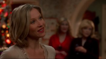 Movie still from “Surviving Christmas” (2004), directed by Mike Mitchell – A woman smiles at the camera in front of other women; Close Up shot, Over the shoulder angle