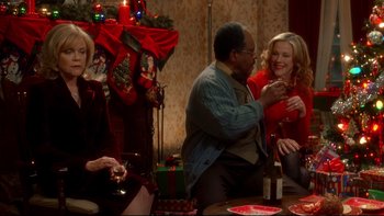 Movie still from “Surviving Christmas” (2004), directed by Mike Mitchell – A group of people sitting at a table with presents; Medium shot, Over the shoulder angle