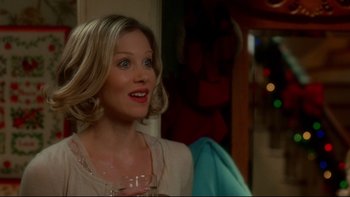 Movie still from “Surviving Christmas” (2004), directed by Mike Mitchell – A woman is holding a wine glass and smiling for the camera; Close Up shot, Over the shoulder angle