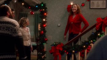 Movie still from “Surviving Christmas” (2004), directed by Mike Mitchell – Two women standing at the bottom of a stair railing in front of christmas lights; Wide shot, Over the shoulder angle
