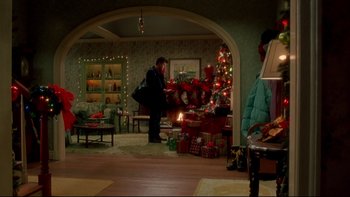 Movie still from “Surviving Christmas” (2004), directed by Mike Mitchell – A man standing next to a christmas tree in a living room; Extreme Wide shot, High angle