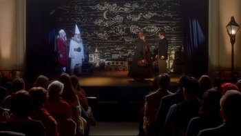 Movie still from “Surviving Christmas” (2004), directed by Mike Mitchell – A group of people on a stage in front of an audience; Wide shot, High angle