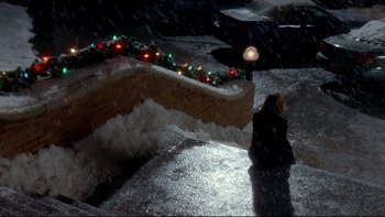 Movie still from “Surviving Christmas” (2004), directed by Mike Mitchell – A woman sitting on the ground in the rain; Extreme Wide shot, High angle
